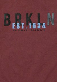 Tejido burdeos con el audaz texto negro "BRKLN" y "EST. 1634." en azul claro impreso abajo en negro. Diseño simple y casual.