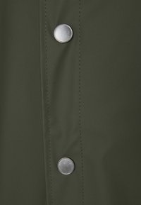 Dark green fabric with a smooth texture, featuring two metallic snaps and visible stitching along the edges.