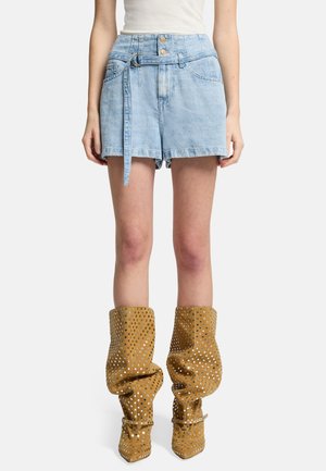 Lichtblauwe denim high-waisted shorts met een strikceintuur, voorzien van een klassieke vijf-pocketdesign en iets rafelige zoom. Gecombineerd met textuur, gestudde beige enkellaarsjes.