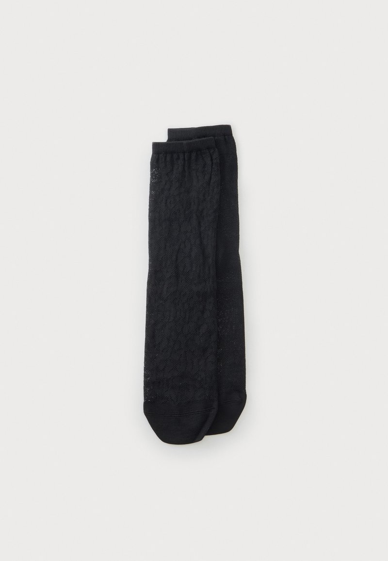 Paire de chaussettes noires montantes avec un motif léopard subtil, posées à plat sur un fond clair uni.