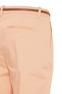 Persiko spalvos kelnės su ruda diržu, rodančios užpakalinę paslėptą kišenę ir šoninio siūlės detalę prieš baltą foną.
