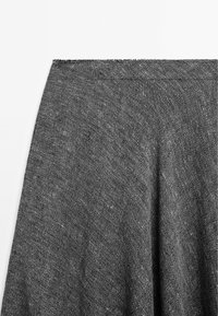 Tessuto di maglia grigia con una sottile texture e un orlo leggermente irregolare. Il materiale appare morbido e cade con delicatezza.
