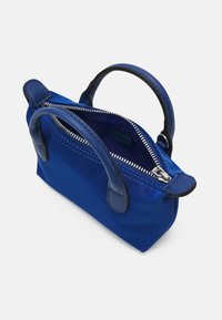 Petit sac à main bleu avec deux anses texturées et une fermeture éclair argentée partiellement ouverte sur fond blanc.