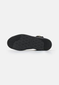 Černá podešev sneakers s texturovaným vzorem; obsahuje trojúhelníkové vzory a otisk loga. Odolný gumový materiál.