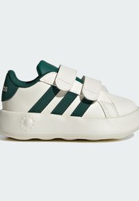 Zapatillas blancas con detalles en verde, que cuentan con dos tiras de velcro, tres franjas verdes, suela redondeada y textura de cuero suave.
