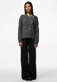 Tamsiai pilkas megztas kardiganas su raukšlėta tekstūra, su sagų uždarymu, dviem priekinėmis kišenėmis ir laisvu siluetu. Su juodomis plačiomis kelnėmis.