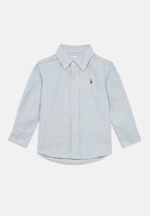 Camisa de botões de manga comprida com riscas verticais azuis e brancas e logótipo castanho bordado no peito esquerdo.