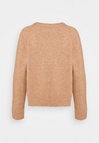 Pull en tricot beige avec un col rond, des manches longues et un ourlet court. La texture semble douce et légèrement duveteuse.