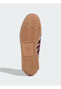 Adidase kinga tald on kummist, millel on tekstureeritud siksakmuster. Keskosas on logo ja kontrastne burgundia punase triibuga disain.