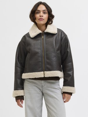 Giacca in finta pelle marrone con colletto e polsini in shearling crema, design corto, dotata di zip frontale e dettagli in maglia scura.