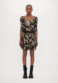 Black dress with yellow and white floral patterns, scoop neckline, three-quarter sleeves, pleated skirt, paired with black ankle boots.