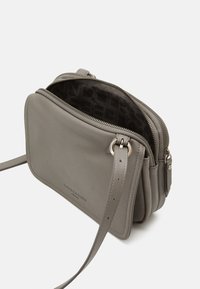 Szara skórzana torba na ramię z teksturowaną powierzchnią, wieloma komorami na zamek błyskawiczny oraz regulowanym paskiem. Wnętrze ma wzorzystą podszewkę.