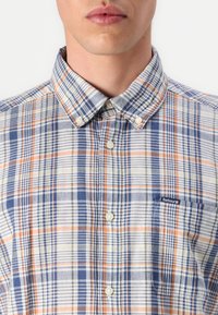 Πουκάμισο κοντομάνικο σε καρό σχέδιο, σε μπλε, πορτοκαλί και λευκό χρώμα. Διαθέτει κολάρο με κουμπιά, μπροστινό κλείσιμο με κουμπιά και μικρό λογότυπο στην τσέπη του στήθους.