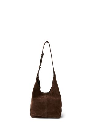 Weiche braune Wildleder-Schultertasche mit verstellbarem Riemen und lässiger Form, die aufrecht vor weißem Hintergrund steht.