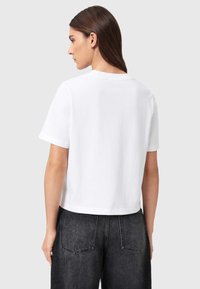 Λευκό, κοντομάνικο μπλουζάκι από απαλό βαμβάκι με κοντά μανίκια και στρογγυλή λαιμόκοψη. Φορεμένο με μαύρο τζιν ψηλόμεσο με πίσω τσέπες.