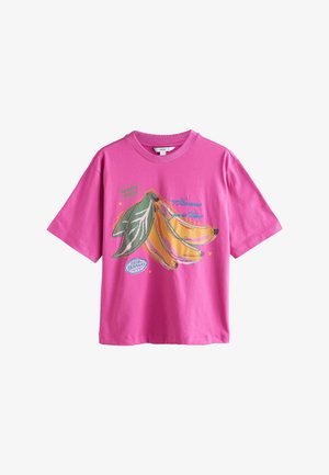 Bright pink short-sleeve t-shirt with graphic of three yellow bananas and green leaves, featuring text "Harvest good times" and small hearts.