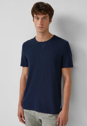 Navyblauw T-shirt met korte mouwen van textuurstof, voorzien van een ronde hals en subtiele naaddetails. Minimale branding aan de onderkant.