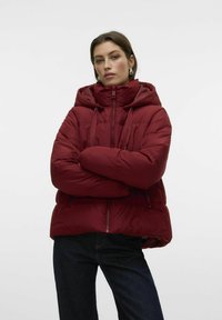 Bordeaux puffer-jakke med høy krage og snøring, med glidelås foran og sidelommer, leicht oversized passform, myk tekstur.