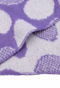 Coperta decorativa con motivo a pois grandi viola su sfondo bianco, realizzata in un morbido tessuto testurizzato con bordi cuciti.
