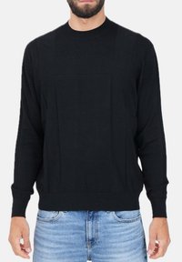 Maglione nero con scollatura rotonda, polsini a costine e design con pannelli testurizzati. Realizzato in materiale morbido, abbinato a jeans blu chiaro.
