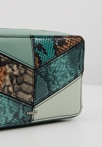 Borsa a tracolla in patchwork verde e marrone con texture in finta pelle di serpente e pelle liscia, e un piccolo logo dorato "PARFOIS".