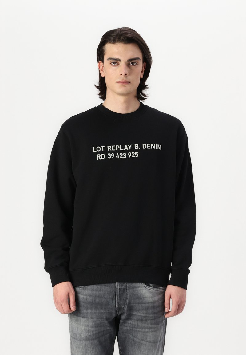 Sudadera negra con cuello redondo y mangas largas, que presenta texto impreso en blanco: "LOT REPLAY B. DENIM RD 39 423 925."