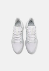 White athletic shoes with a mesh upper, textured toe cap, and flat laces. Features a cushioned sole and minimalistic design details.