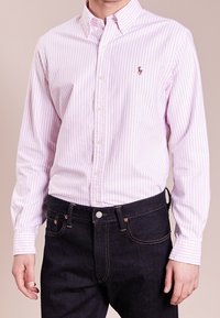 Ljust rosa och vitrandig skjorta med knappar, i bomullstyg, klassisk krage, enstaka bröstemblem, matchad med mörka denimjeans.