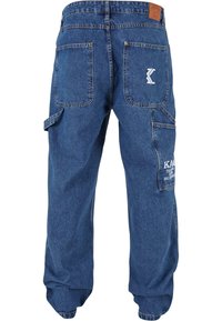 Pantalones cargo de denim en azul oscuro con varios bolsillos, incluyendo dos bolsillos traseros y un bolsillo lateral. Presenta detalles de logo en la parte posterior.