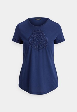 Marineblå T-skjorte med korte ermer, oppbrettede mansjetter og forhøyet brodert våpenskjold på brystet under en rund halslinning.