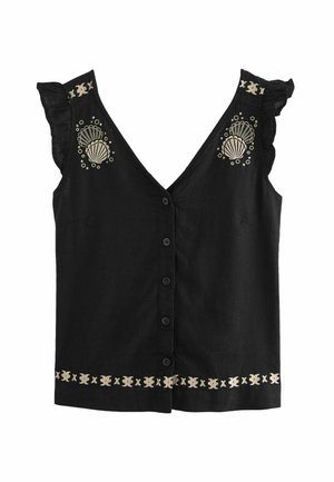 Blouse noire sans manches avec boutons sur le devant, épaules à volants, et motifs brodés beiges en forme de coquillage et géométriques sur la poitrine et l'ourlet.