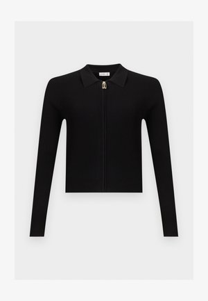 Schwarzer gerippter Strick-Cardigan mit langen Ärmeln, spitzem Kragen und zentralem goldfarbenem Reißverschluss, flach auf einem einfarbigen hellen Hintergrund gelegt.