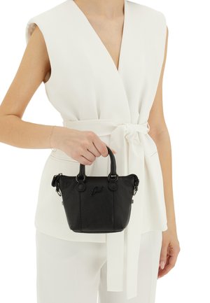 Borsa a mano in pelle nera con finitura a pietra, manici arrotondati, hardware argentato e logo incastonato; abbinata a una camicia bianca con cintura.