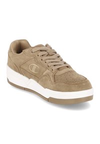 Beige suède sneaker met een ronde neus, een gladde witte tussenzool en een gestructureerde zool. Voorzien van een veterontwerp en geperforeerde details op de neus.