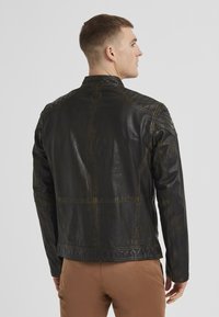 Schwarze Lederjacke mit einer Vintage-Textur, featuring gesteppte Schulterakzente und einen Stehkragen. Sichtbare Nähte entlang der Nähte.
