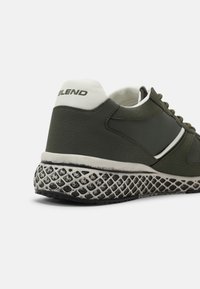 Green athletic shoe with textured upper, white accents, and a patterned rubber outsole. Features "BLEND" logo on heel.