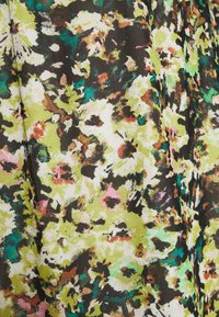 Gros plan sur un tissu avec un imprimé floral abstrait en vert, jaune, noir, blanc, rose et bleu sarcelle, présentant un motif texturé et coloré.