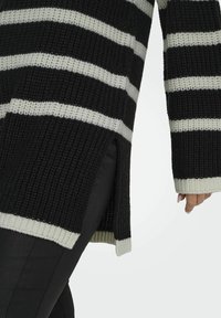 Zwart-wit gestreepte gebreide oversized trui met een losse pasvorm, zijslitsen en ribgebreide manchetten en zoom. Kenmerkt zich door een gestructureerd, geweven patroon.