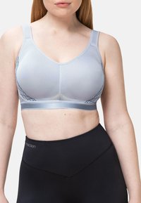 Lichtblauwe sportbeha met een mesh-textuur, v-hals ontwerp en verstelbare bandjes, gecombineerd met hoge zwarte leggings.