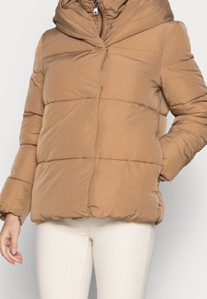 Bruine gewatteerde jas met hoge kraag en ritssluiting, gedragen met een witte broek, getoond van halverwege de torso tot de heupen tegen een effen achtergrond.