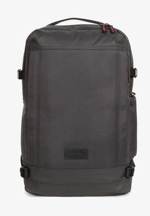 Mochila negra hecha de nylon texturizado, con forma rectangular, parche de logo en la parte frontal, correas ajustables y bolsillos laterales.