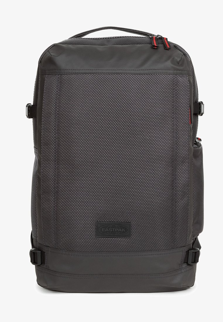 Sac à dos noir en nylon texturé, de forme rectangulaire, avec un écusson logo à l'avant, des bretelles réglables et des poches latérales.