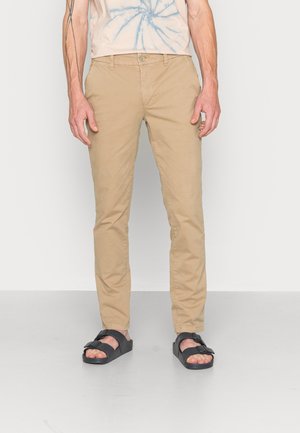 Beige katoenen chinos met een slim fit ontwerp, voorzien van een knoopsluiting, voorzakken en zwarte sandalen met een dubbele bandontwerp.