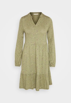 Vestido verde con mangas largas, escote en V y cuello con volantes. Presenta patrones florales y un diseño con volantes en el dobladillo. Textura de tela suave.