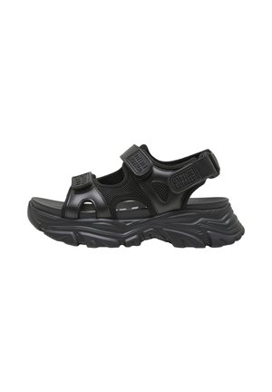 Sort sandal med chunky sål og justerbare stropper lavet af læder og mesh, mærket med "Buffalo" på stropperne.