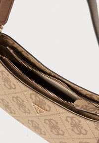 Brązowa torebka na ramię w wzory, wyposażona w zasuwaną na zamek komorę, złote elementy oraz teksturowaną tkaninę z detalem logo marki.