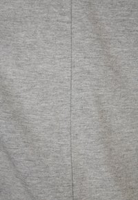 Gros plan sur un tissu uni gris clair avec une couture centrale verticale au milieu.