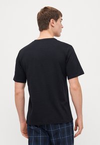 T-shirt en coton noir à manches courtes et col rond, avec une texture lisse et une coupe décontractée vue de dos.