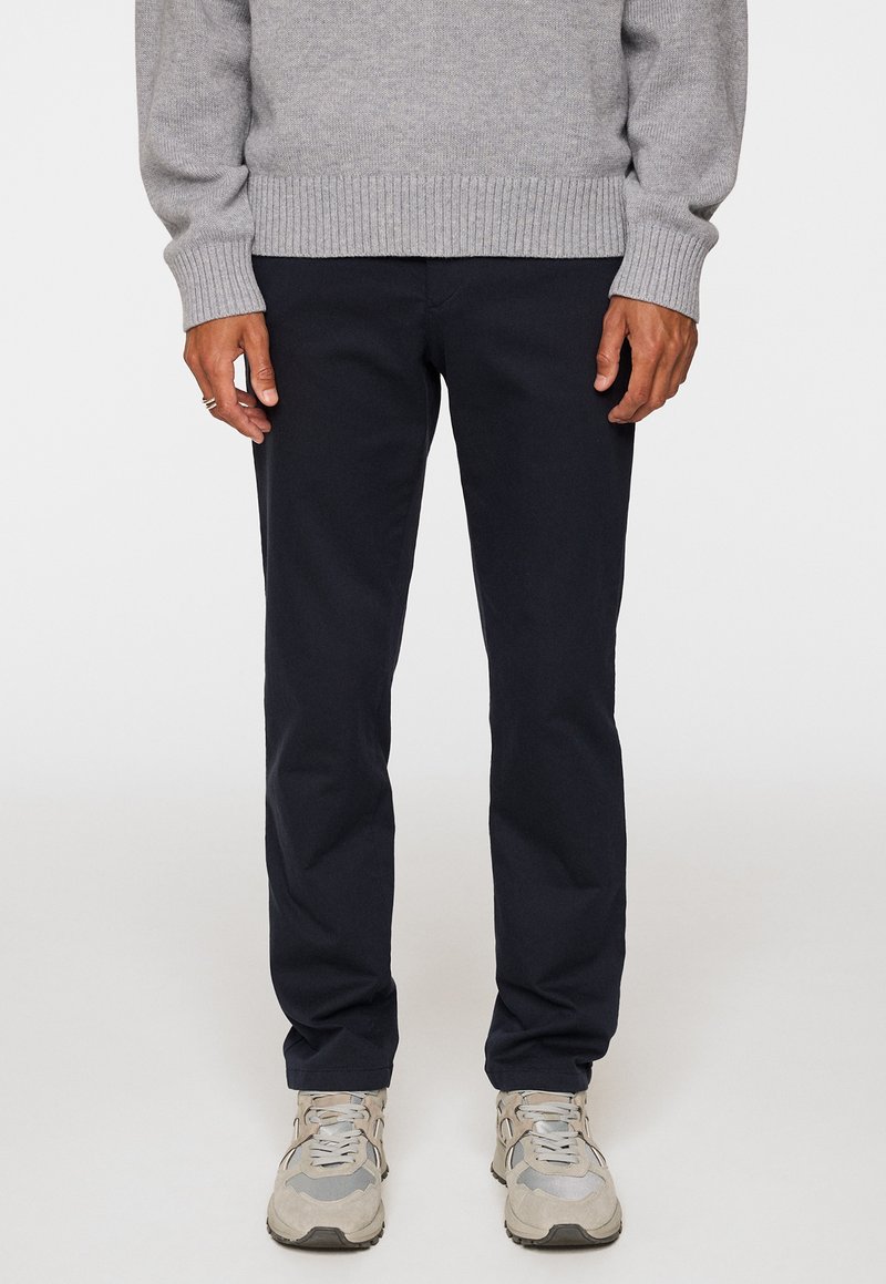 Navy chinos made of cotton twill with a straight-leg fit. Features front and back pockets, subtle stitching, and a smooth texture.