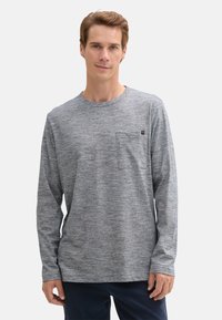 Langarmshirt aus meliertem grauen Stoff, mit Rundhalsausschnitt, einer Brusttasche und einem lockeren Schnitt mit Raglanärmeln.